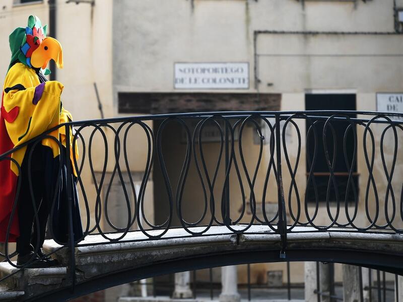 Masked revellers cross a bridge during the opening of the Venice Carnival on February 09, 2020. The carnival in Venice takes place until February 25, 2020. Vincenzo PINTO / AFP