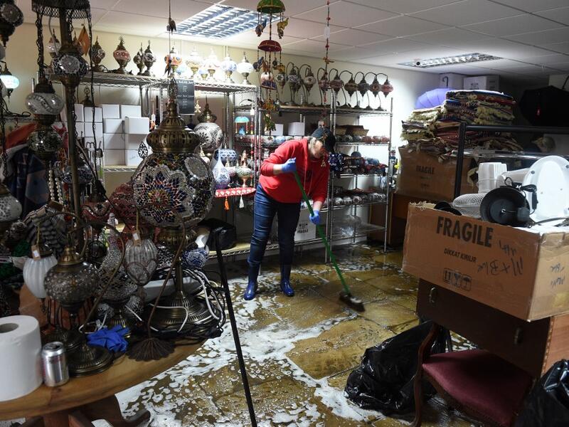 A woman sweeps water from the floor during the clean-up efforts at a business in Hebden Bridge, northern England, on February 10, 2020 after the flooding brought by Storm Ciara. Storm Ciara grounded hundreds of flights Monday and left swatches of Europe without power after unleashing torrential rain and causing flash flooding that cancelled football matches in Britain. Oli SCARFF / AFP