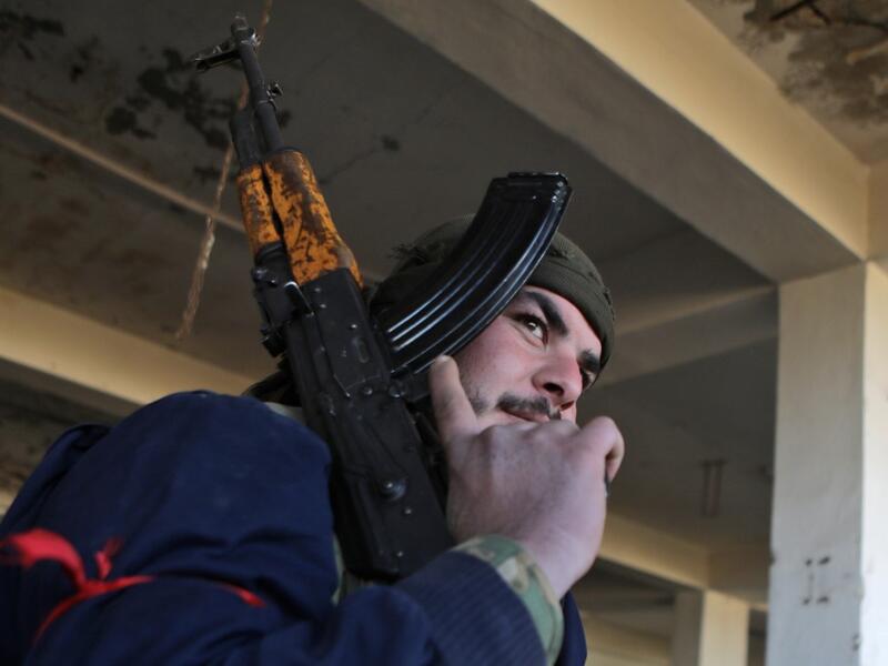 A Turkish-backed Syrian fighter carries a riffle at a position east of Idlib city in northwestern Syria on February 20, 2020 amid ongoing regime offensive on the last major rebel bastion in the country's northwest.  Bakr ALKASEM / AFP