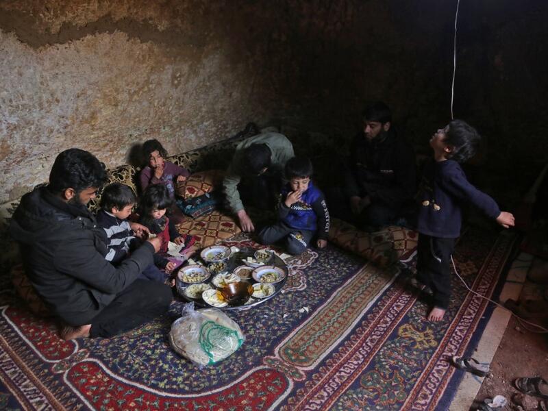 Members of a family of internally displaced Syrians eat together in an underground shelter where several families from Aleppo and Idlib provinces are taking refuge, in the village of Taltunah about 15 kilometres northwest of Idlib in the northwestern Idlib province, on February 23, 2020. Aref TAMMAWI / AFP