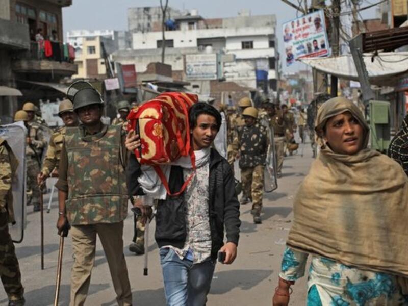 An Indian Muslim family leaves the area as Indian paramilitary soldiers patrol a street vandalized in Tuesday's violence in New Delhi, India, Thursday, Feb. 27, 2020. (AP Photo)