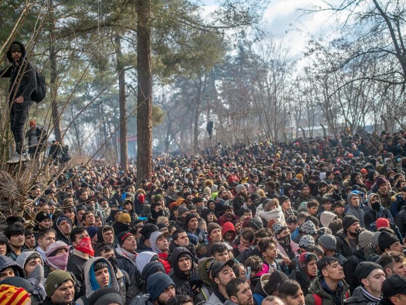 Migrants watch Greek police during clashes as they gather at the buffer zone Turkey-Greece border, at Pazarkule, in Edirne district, on February 29, 2020. Thousands of migrants stuck on the Turkey-Greece border clashed with Greek police on February 29, 2020, according to an AFP photographer at the scene. BULENT KILIC / AFP