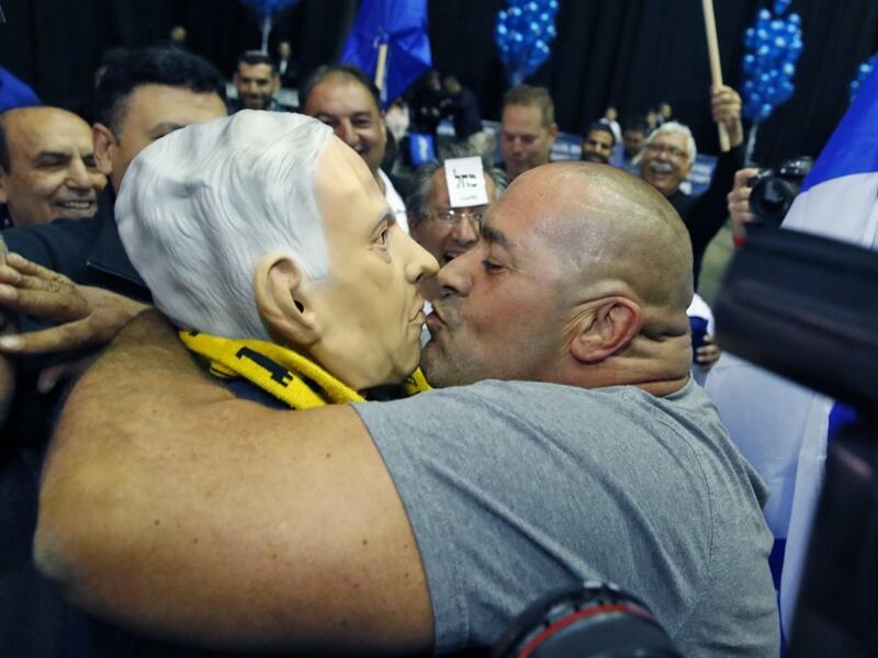 A man kisses another wearing a "Benjamin Netanyahu" face mask as they celebrate at the Likud party's electoral headquarters in the coastal city of Tel Aviv on March 2, 2020, after polls officially closed. Netanyahu appeared to lead his main challenger following elections with multiple exit polls putting his right-wing Likud several seats ahead of the centrist Blue and White party. Exit polls by three Israeli television networks, released after polls closed, gave Likud between 36 and 37 seats in Israel's 120