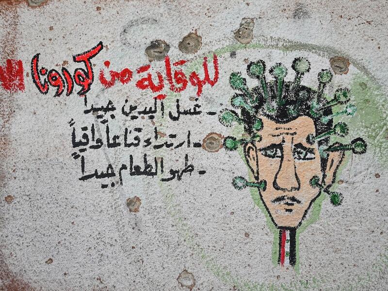 A graffiti portraying President Bashar al-Assad as the coronavirus is seen on the wall of a destroyed school in Binnish town in Syria’s northwestern Idlib province near the Turkish border, on March 10, 2020. Ozan KOSE / AFP
