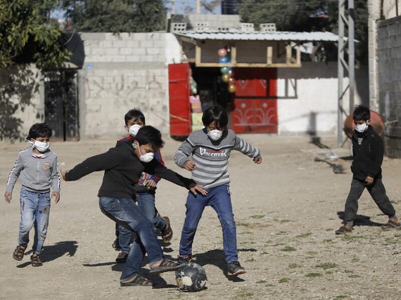 Boys wearing protective and N95 masks play with a football outside their homes in Gaza City on March 22, 2020. MOHAMMED ABED / AFP