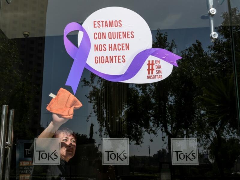 A woman cleans the glass door of a Mexico City restaurant with a sign reading 'We stand with those who make us giants' during Monday's 'A Day Without Us' protest (AFP)