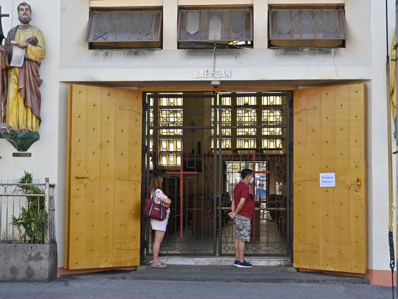 People wearing face masks stand and pray outside an empty Quiapo church, usually filled with devotees during Fridays but now closed due to restrictions to stop the spread of the COVID-19 coronavirus, in Manila on March 27, 2020. Catholic church authorities closed all its churches in line with the government's imposed enhanced quarantine as a preventive measure against COVID-19. Ted ALJIBE / AFP