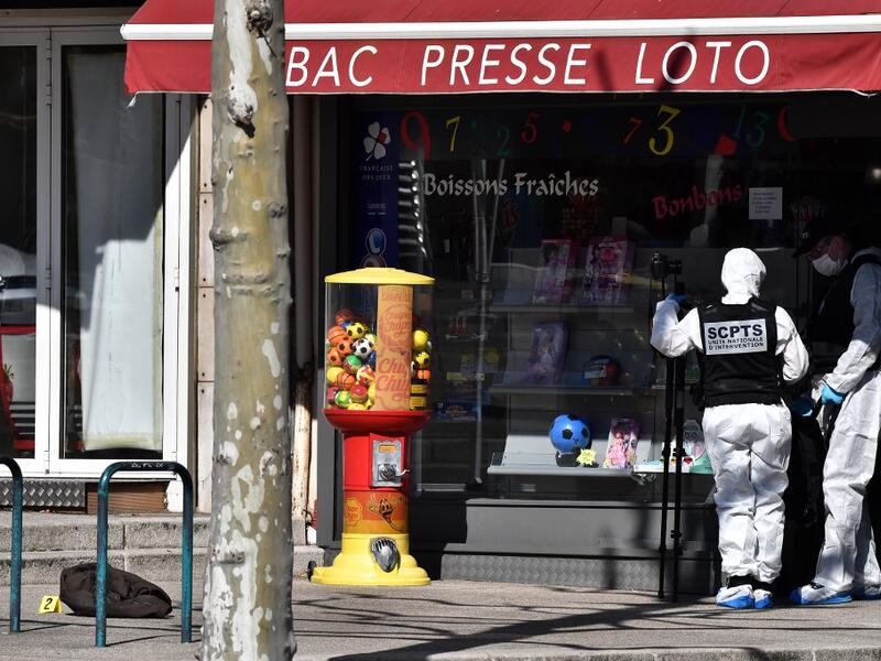 A French Police Judiciaire officer wearing a protective suits holds a camera on a tripod in the centre of Romans-sur-Isere, on April 4, 2020, after a man attacked several people with a knife, killing two and injuring seven before being arrested, according to sources close to the investigation. JEFF PACHOUD / AFP