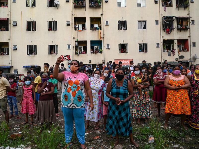 Residents watch a music band formed by Sri Lankan Navy personnel as they play outside a housing complex during a government-imposed nationwide lockdown as a preventive measure against the COVID-19 coronavirus, in Colombo on April 9, 2020. ISHARA S. KODIKARA / AFP