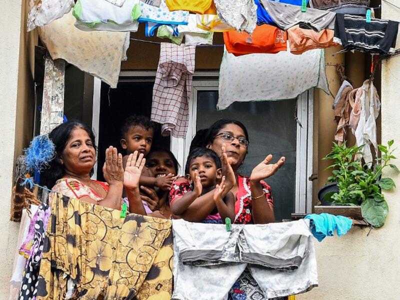 Residents watch from their flat's window a music band formed by Sri Lankan Navy personnel as they play outside a housing complex during a government-imposed nationwide lockdown as a preventive measure against the COVID-19 coronavirus, in Colombo on April 9, 2020. ISHARA S. KODIKARA / AFP