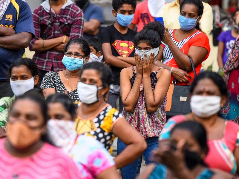 Residents wearing facemasks watch a music band formed by Sri Lankan Navy personnel as they play outside a housing complex during a government-imposed nationwide lockdown as a preventive measure against the COVID-19 coronavirus, in Colombo on April 9, 2020. ISHARA S. KODIKARA / AFP