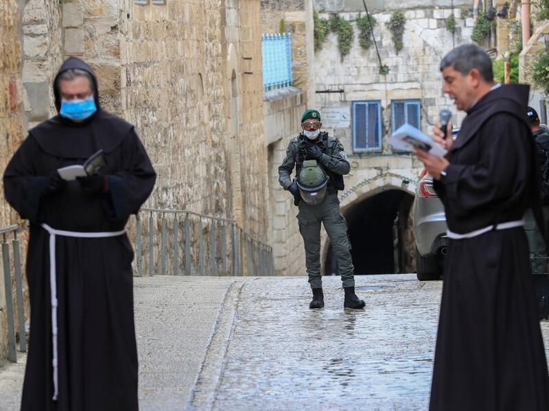 An Israeli soldier stands guard as Fransiscan friars pray at the first station while taking part in a small Procession of the Way of the Cross along the Via Dolorosa to mark Good Friday in Jerusalem, on April 10, 2020, amid the COVID-19 outbreak. All cultural sites in the Holy Land are shuttered, regardless of their religious affiliation, as authorities seek to forestall the spread of the deadly respiratory disease, which will prevent Christians from congregating for the Easter service, this coming Sunday f