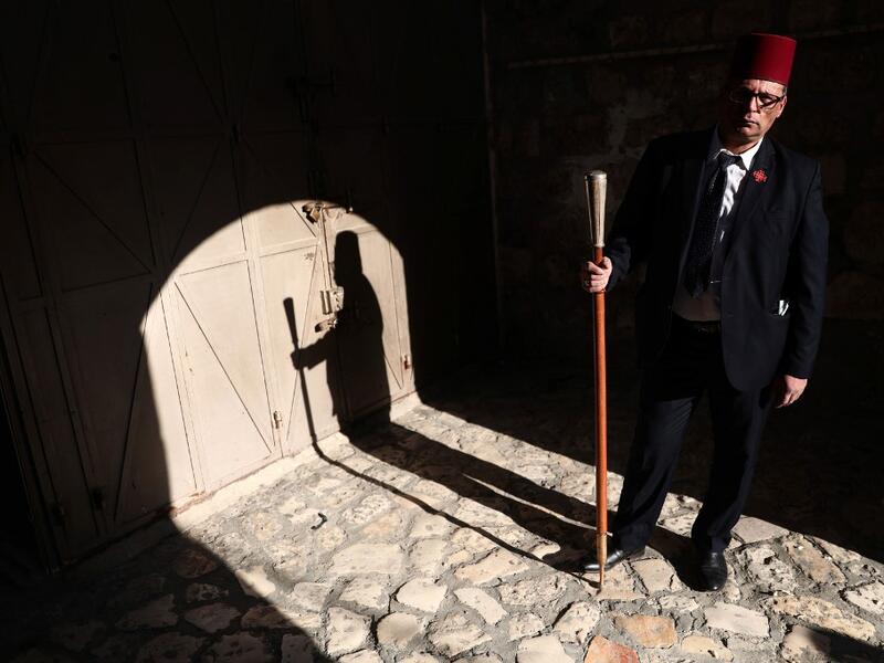 The Kawas of the Franciscan order waits for a priest by the entrance of the yard of the Church of the holy Sepulchre in Jerusalem's Old City on April 9, 2020, amid the COVID-19 pandemic. All cultural sites in the Holy Land are shuttered, regardless of their religious affiliation, as authorities seek to forestall the spread of the deadly respiratory disease, which will prevent Christians from congregating for the Easter service, this coming Sunday for Catholic worshippers, then a week later on April 19 for O