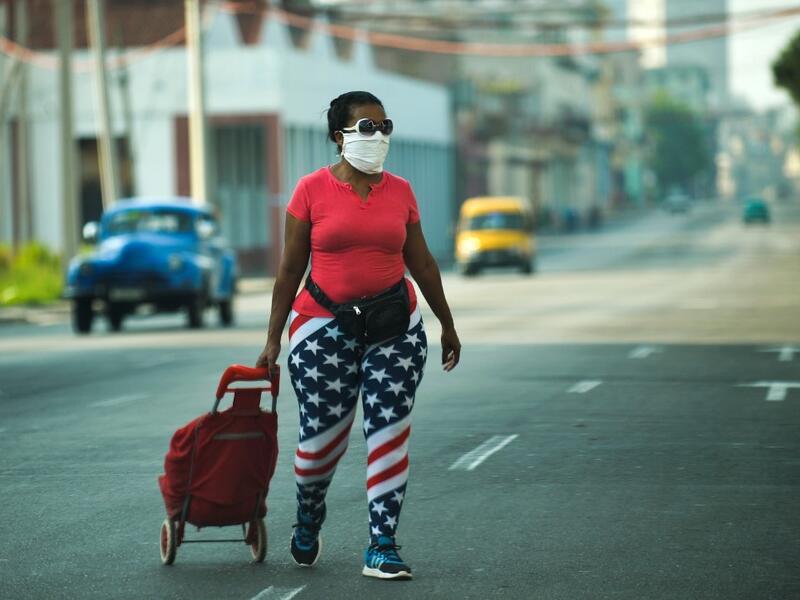 A woman wearing tights depicting the US flag and a face mask, walks along a street in Havana, on April 13, 2020. While Cuba tries to stop the spread of the coronavirus on the island, with 726 cases, voices can be heard to demand the lifting of the US embargo to facilitate the arrival of medical products. YAMIL LAGE / AFP