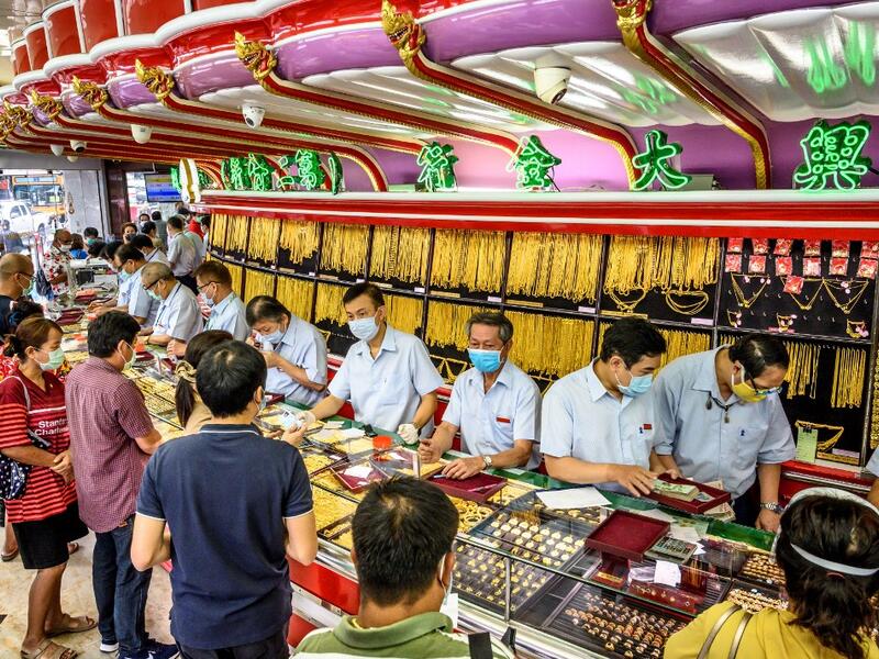 People wearing face masks amid fears of the spread of COVID-19 coronavirus sell their jewelries in a gold shop in Bangkok's Chinatown on April 15, 2020. Hundreds of Bangkok residents rushed to goldsmith shops in order to sell their jewelries as gold prices reached its highest levels since 2012. Mladen ANTONOV / AFP
