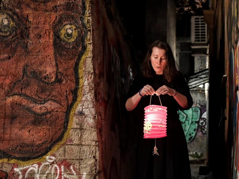A woman lights a candle with a "Holy Fire" from small candles left on a path outside the Metochion (embassy church) of the Holy Sepulchre in Athens, where the Holy Light was brought earlier today from Jerusalem for the resurrection service on April 18, 2020 as part of the Orthodox Easter celebrations. The strict quarantine measures against the spread of the COVID-19 (the novel coronavirus) keeps churches empty during the Orthodox Easter services and faithfuls are not allow to light their candles with the Ho