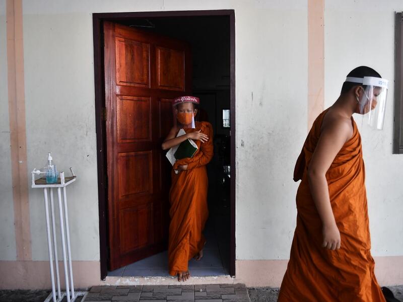 Novice monks wearing face shields as a preventive measure against the spread of the COVID-19 coronavirus leave the classroom after religious studies at Wat Molilokkayaram Buddhist temple in Bangkok on April 20, 2020. Lillian SUWANRUMPHA / AFP
