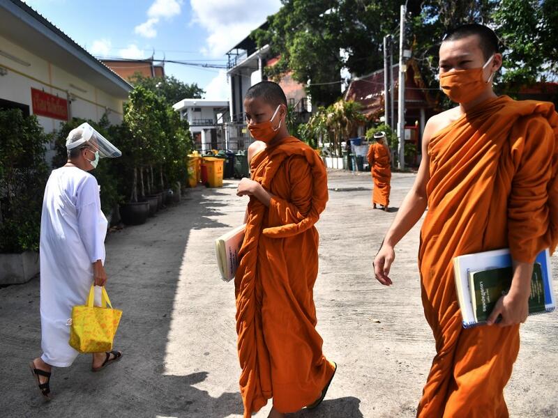 Novice monks wearing masks as a preventive measure against the spread of the COVID-19 coronavirus walk around after religious studies at Wat Molilokkayaram Buddhist temple in Bangkok on April 20, 2020. Lillian SUWANRUMPHA / AFP