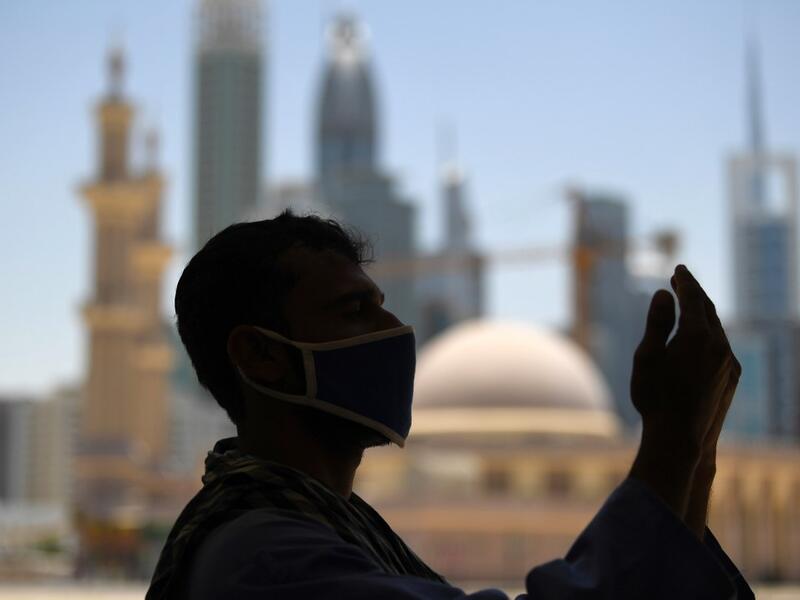 A mask-clad Muslim worker prays near a mosque on the first Friday of the holy fasting month of Ramadan, amidst a curfew due to the COVID-19 coronavirus pandemic, in Dubai on April 24, 2020. KARIM SAHIB / AFP