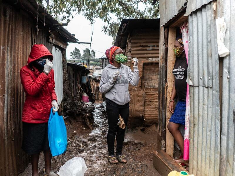 Florence Akiuor (2nd L) of Coalition for grassroots human rights defenders Kenya (CGHRD'S Kenya) explains how to use a mask during their food distribution. (AFP)