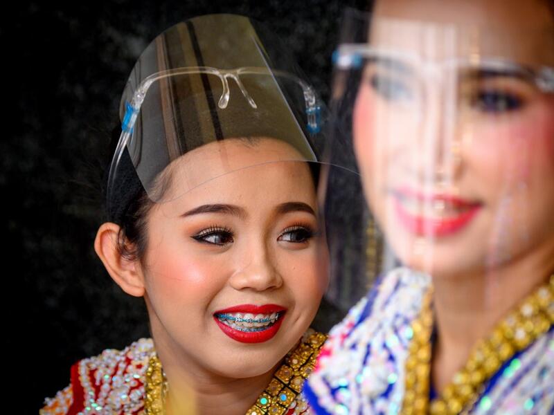 Traditional Thai dancers wearing protective face shields relax after a performance at the Erawan Shrine, which was reopened after the Thai government relaxed measures to combat the spread of the COVID-19 novel coronavirus, in Bangkok on May 4, 2020. Thailand began easing restrictions related to the COVID-19 novel coronavirus on May 3 by allowing various businesses to reopen, but warned that the stricter measures would be re-imposed should cases increase again. Mladen ANTONOV / AFP