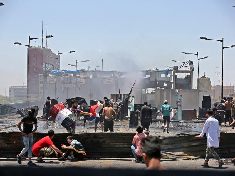 Iraqi protesters take cover as they clash with security forces during an anti-government demonstration on Al-Jumhuriyah bridge in the capital Baghdad, on May 10,2020. Modest anti-government rallies resumed in some Iraqi cities today, clashing with security forces and ending months of relative calm just days after Prime Minister Mustafa Kadhemi's government came to power. AHMAD AL-RUBAYE / AFP