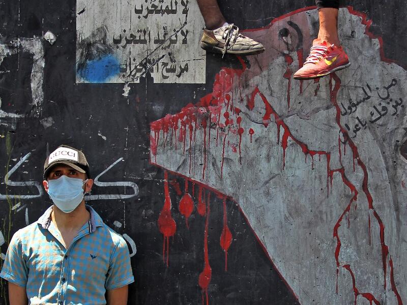 An Iraqi protester, wearing a protective mask, is pictured on the Al-Jumhuriyah bridge in the capital Baghdad on May 11, 2020, during an anti-government demonstration. AHMAD AL-RUBAYE / AFP