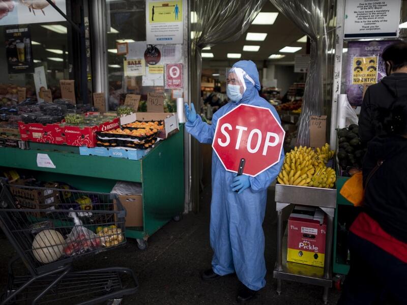 A worker wearing a full body suit holds a STOP sign in front of a Food market as he manages the flow of the customers on May 18, 2020 in the Jackson Heights neighbourhood of Queens in New York City. Johannes EISELE / AFP