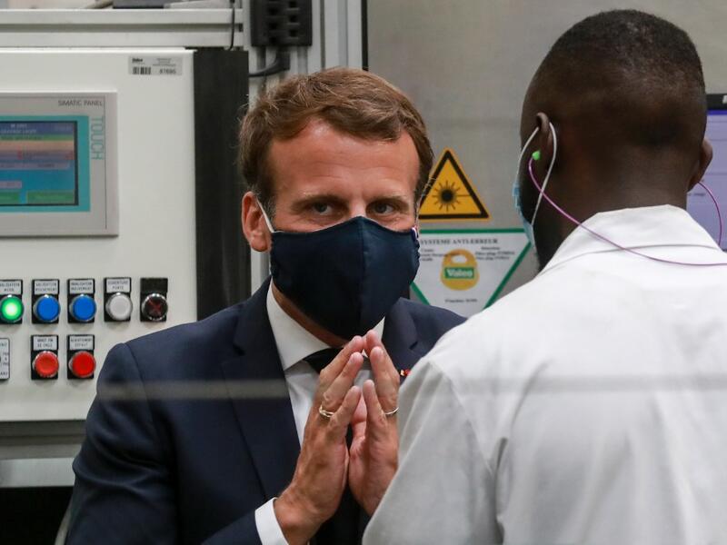 French President Emmanuel Macron, wearing a face mask, speaks to a worker as he visits the factory of manufacturer Valeo in Etaples, near Le Touquet, northern France on May 26, 2020 as part of the launch of a plan to rescue the French car industry. Ludovic MARIN / POOL / AFP
