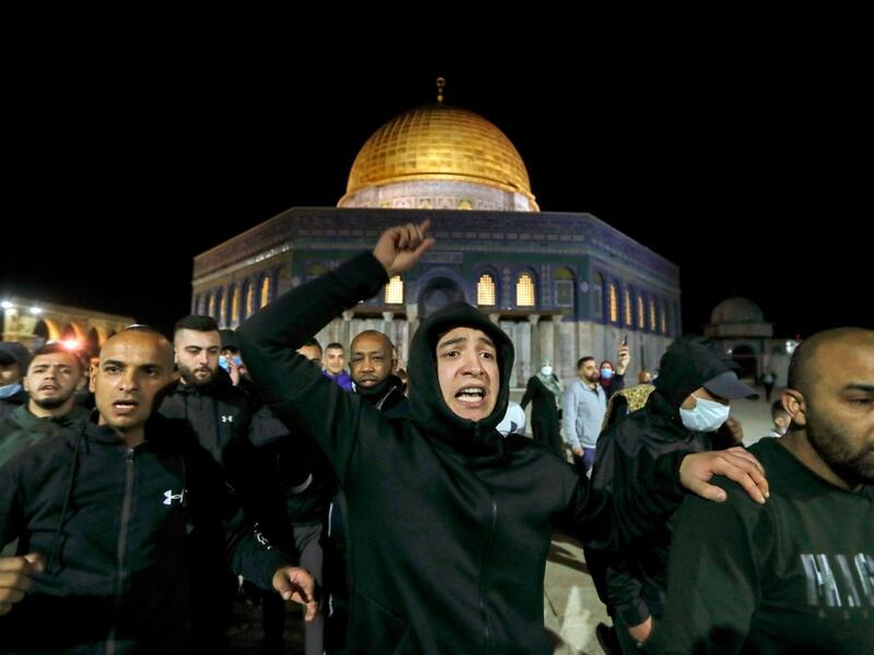 Palestinian men react as they walk in front of the Dome of Rock at the Al-Aqsa Mosque compound, before the start of the dawn prayer (salat al-fajr) inside the compound in Jerusalem's Old City, on May 31, 2020, after a two-month closure due to the COVID-19 pandemic. AHMAD GHARABLI / AFP