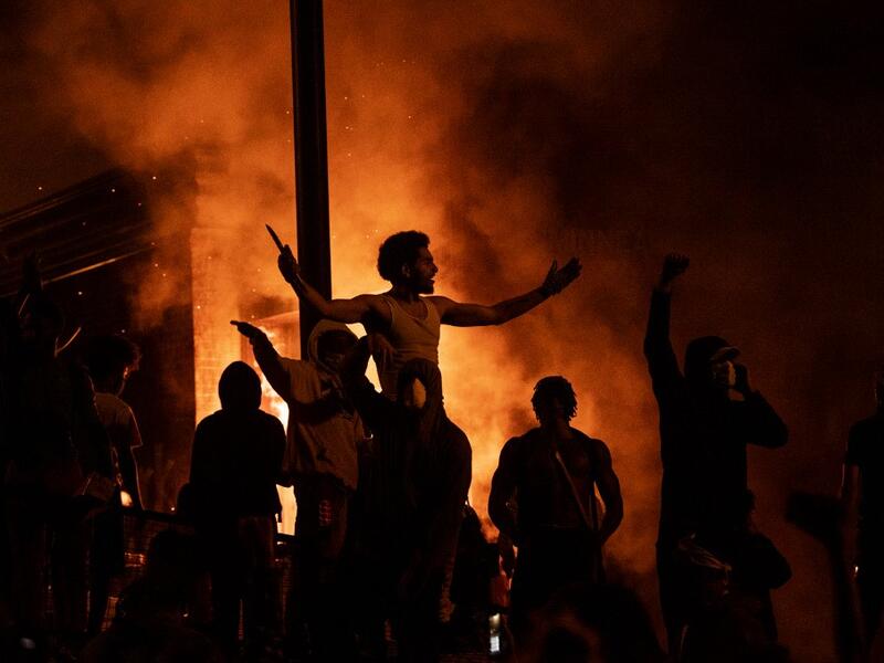 Protesters cheer as the Third Police Precinct burns behind them on May 28, 2020 in Minneapolis, Minnesota. As unrest continues after the death of George Floyd police abandoned the precinct building, allowing protesters to set fire to it. Stephen Maturen/Getty Images/AFP Stephen Maturen / GETTY IMAGES NORTH AMERICA / Getty Images via AFP