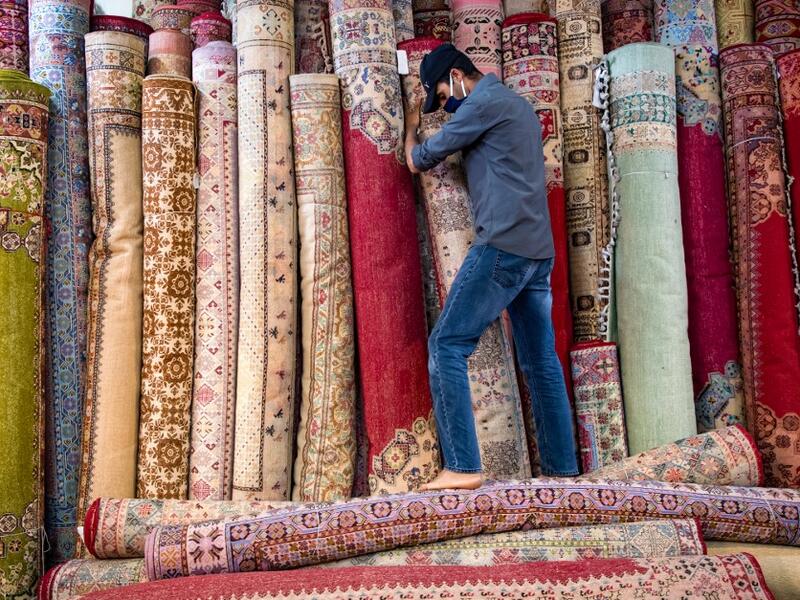 A Moroccan rug dealer lines up carpets at a shop in the city of Sale, north of the capital Rabat, on June 3, 2020, during the novel coronavirus pandemic. Artisans in Morocco have been starved of income for almost three months because of the COVID-19 pandemic. The crafts industry represents some seven percent of GDP, with an export turnover last year of nearly 1 billion dirhams ($100 million). FADEL SENNA / AFP