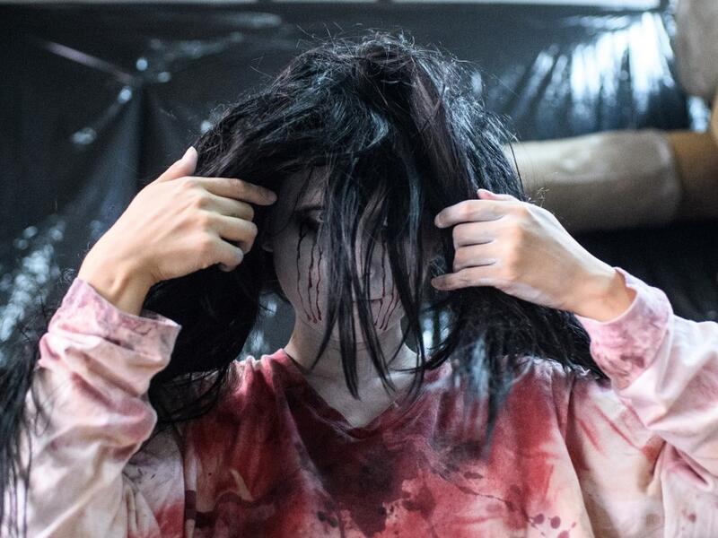 This picture taken on June 15, 2020 shows actress Ayaka Imaide, 34, putting on zombie makeup before a demonstration of a drive-in haunted house at a garage in Tokyo. A car horn beeps and the horror begins: a bloody murder and rampaging zombies. But this drive-in haunted house in Japan protects against the most terrifying enemy of all -- coronavirus. Inside a car, guests can scream as loudly as they like, with no mask required, as hideous creatures daubed in blood swarm towards them.  Philip FONG / AFP
