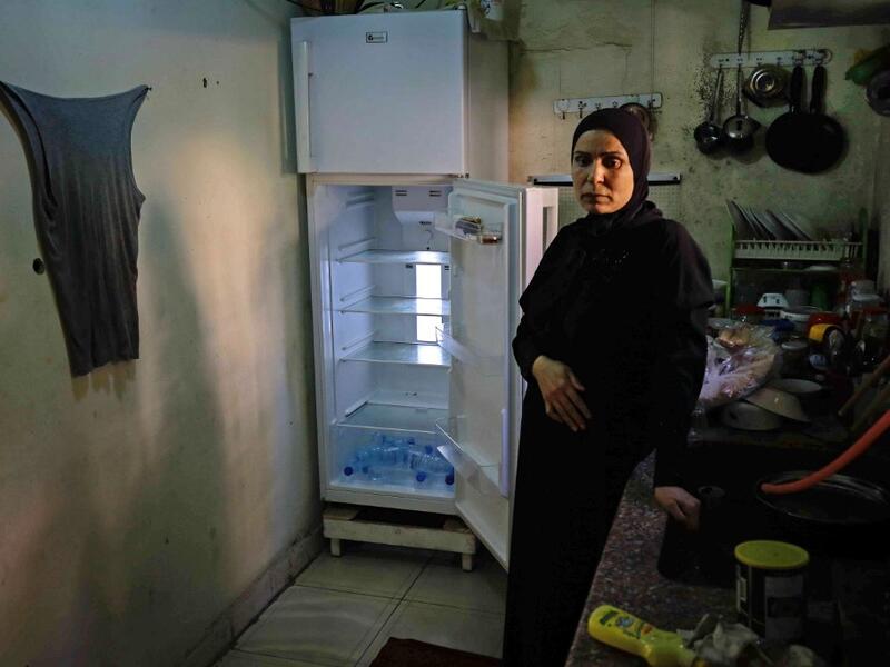 A Lebanese woman stands next to her empty refrigerator in her apartment in the port city of Tripoli north of Beirut on June 17, 2020. Lebanon's economic crisis has led to a collapse of the local currency and purchasing power, plunging whole segments of the population into poverty as exemplified by near-empty fridges in many households. IBRAHIM CHALHOUB / AFP