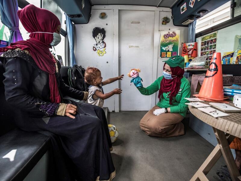 A woman looks on as a worker entertains a homeless child inside one of the mobile units run by the Egyptian authorities and used as part of the "Atfal bala ma'wa" (Children without a home) social program, in the capital Cairo's Abbasia district on June 22, 2020. Khaled DESOUKI / AFP