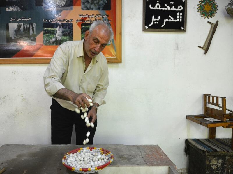 In the green hills of Deir Mama, Saud, his wife and three sons have been making silk for decades. They would raise silk worms in the spring, watching them munch on mulberry tree leaves and slowly build their thick cocoons, before spinning the thread and weaving those coils into fine cloth. MAHER AL MOUNES / AFP