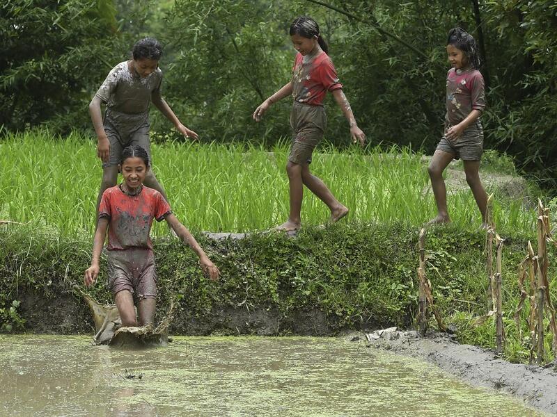 In this photograph taken on June 29, 2020 a mud-covered girls play in a rice paddy field during "National Paddy Day", which marks the start of the annual rice planting season, in Tokha village on the outskirts of Kathmandu. PRAKASH MATHEMA / AFP