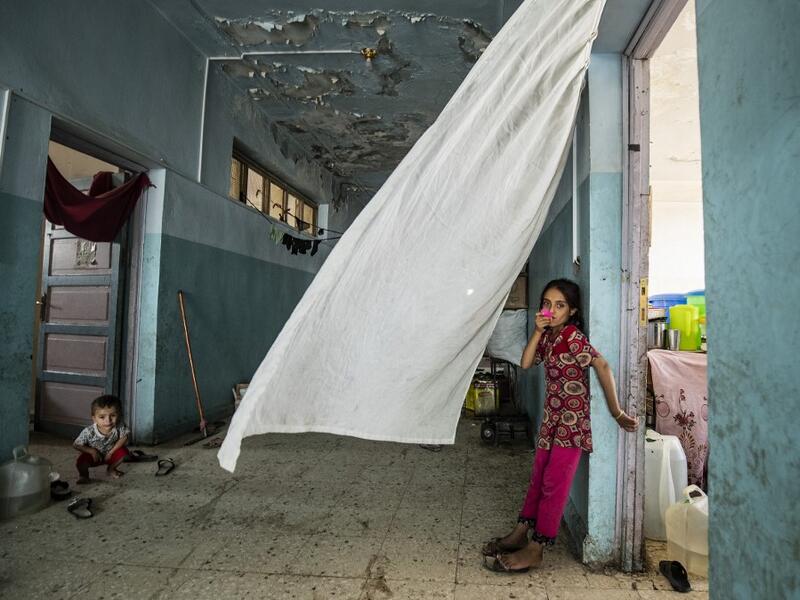 A girl looks on while standing by a doorway at the hallway of a school building where Syrians -- displaced from the area of Ras al-Ain by the Turkish offensive on the northeast -- are staying in the city of Hasakah, on June 30, 2020. Delil SOULEIMAN / AFP