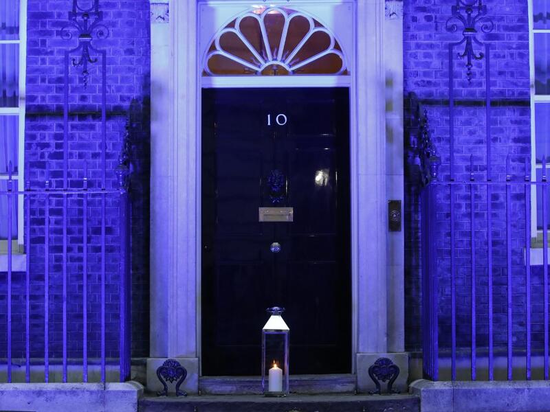 A candle is lit and placed on the doorstep of 10 Downing Street in central London on July 4, 2020 in honour of the tens of thousands of people who have died as a result of the coronavirus pandemic in the UK as the building itself is lit up blue as a tribute to NHS workers and to mark the 72nd anniversary of the NHS. Tolga AKMEN / AFP