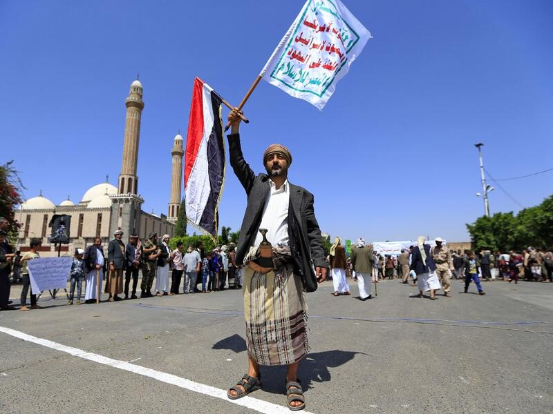 A Yemeni gunman loyal to the Huthi movement lifts flags during a rally in the capital Sanaa, to show support to the movement against the Saudi-led intervention in the country on July, 7, 2020. Mohammed HUWAIS / AFP