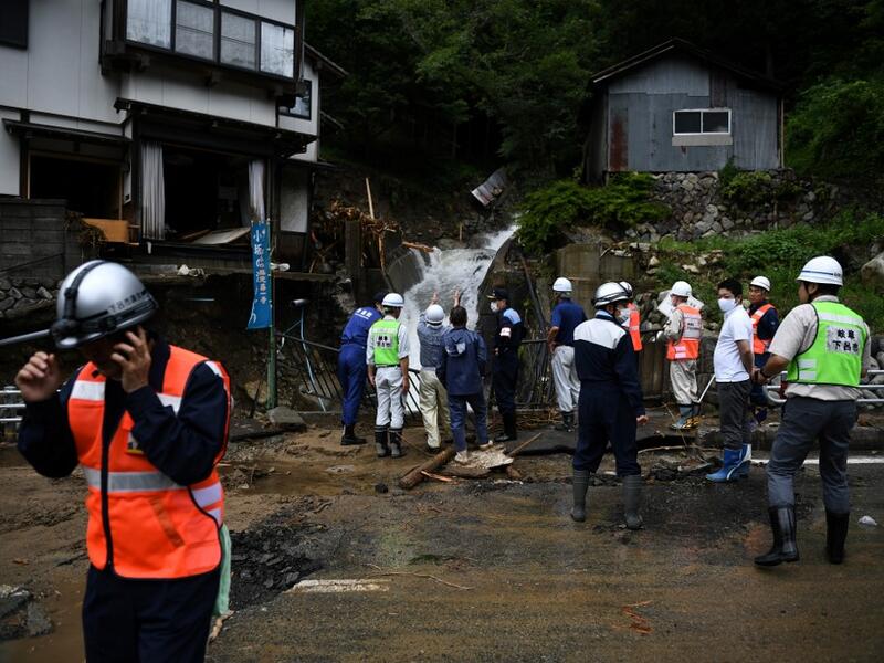 Government officials look at a damaged home following heavy rains and flooding in the village of Gero, Gifu prefecture on July 9, 2020. Japanese emergency services and troops were scrambling to reach thousands of homes cut off by devastating flooding and landslides that have killed dozens and caused widespread damage. Philip FONG / AFP