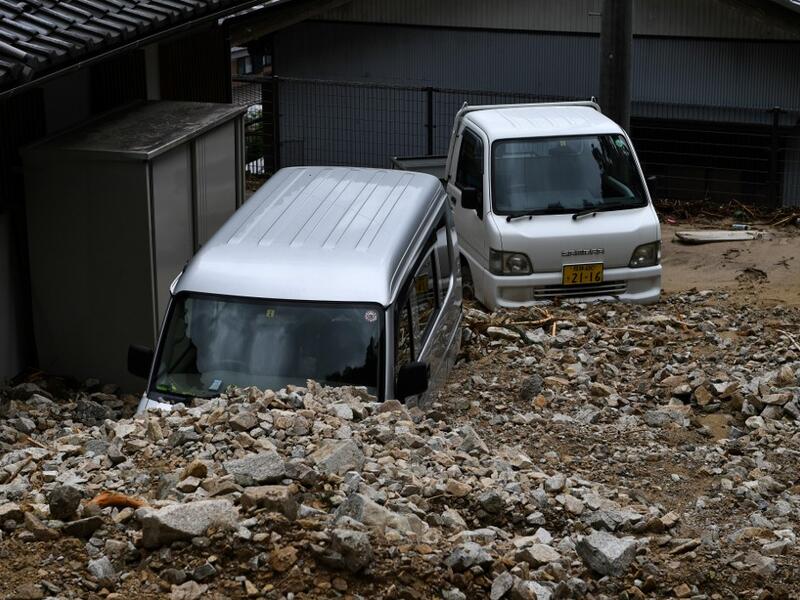 Damaged vehicles are seen under rocks from a mudslide following heavy rains and flooding in the village of Gero, Gifu prefecture on July 9, 2020. Japanese emergency services and troops were scrambling to reach thousands of homes cut off by devastating flooding and landslides that have killed dozens and caused widespread damage. Philip FONG / AFP