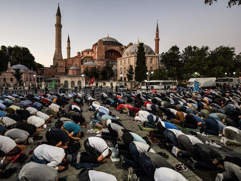 People, some wearing face masks, pray outside the Hagia Sophia museum in Istanbul on July 10, 2020 as they gather to celebrate after a top Turkish court revoked the sixth-century Hagia Sophia's status as a museum, clearing the way for it to be turned back into a mosque. The Council of State, the country's highest administrative court which on July 2 debated a case brought by a Turkish NGO, cancelled a 1934 cabinet decision and ruled the UNESCO World Heritage site would be reopened to Muslim worshipping. The