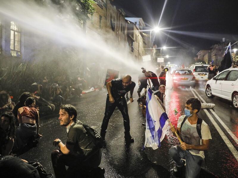 Israeli police spray protesters (clad in masks due to the COVID-19 coronavirus pandemic) with water cannon during an anti-government demonstration in Jerusalem, on July 18, 2020. Ahmad GHARABLI / AFP