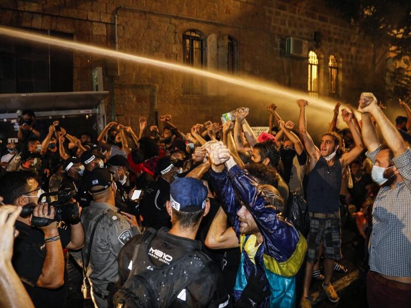 Journalists film as Israeli police spray protesters (clad in masks due to the COVID-19 coronavirus pandemic) with water cannon during an anti-government demonstration in Jerusalem, on July 18, 2020. Ahmad GHARABLI / AFP