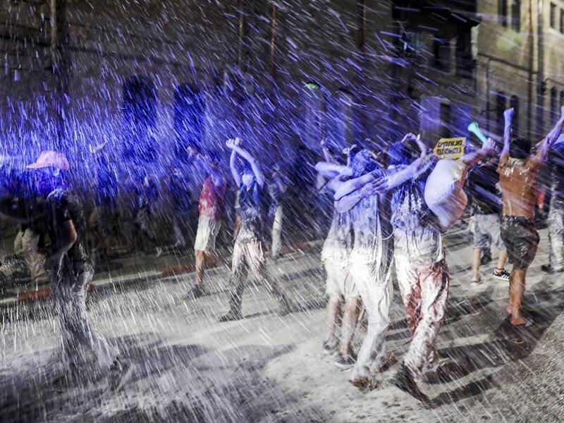 Israeli police spray protesters (clad in masks due to the COVID-19 coronavirus pandemic) with water cannon during an anti-government demonstration in Jerusalem, on July 18, 2020. Ahmad GHARABLI / AFP