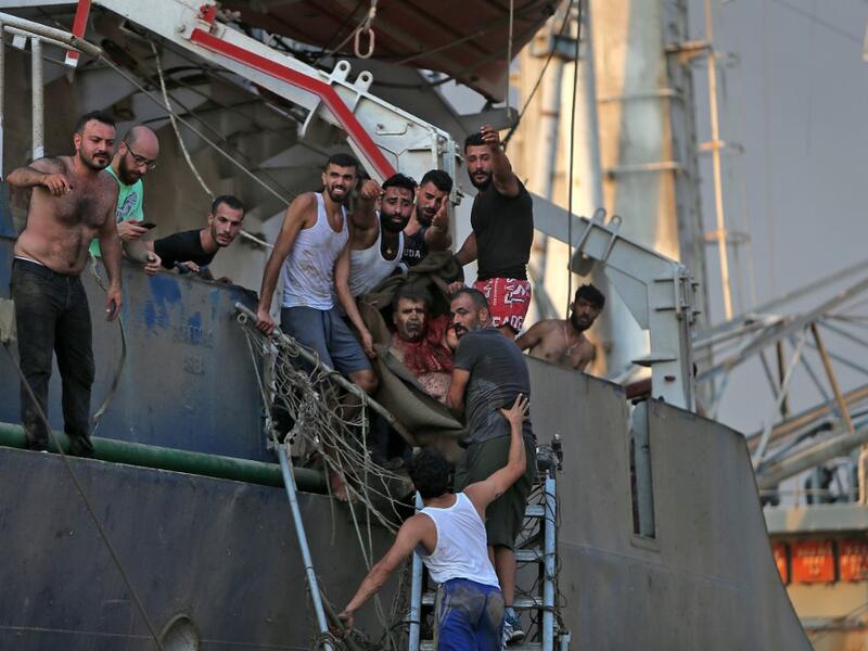 A man is evacuated from a boat following of an explosion near the port in the Lebanese capital Beirut on August 4, 2020. Two huge explosion rocked the Lebanese capital Beirut, wounding dozens of people, shaking buildings and sending huge plumes of smoke billowing into the sky. Lebanese media carried images of people trapped under rubble, some bloodied, after the massive explosions, the cause of which was not immediately known.  STR / AFP