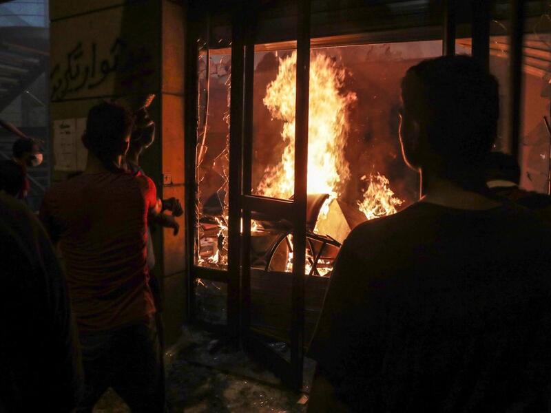 Lebanese protesters watch the flames inside the headquarters of the Lebanese association of banks in downtown Beirut on August 8, 2020, following a demonstration against a political leadership they blame for a monster explosion that killed more than 150 people and disfigured the capital Beirut. ANWAR AMRO / AFP