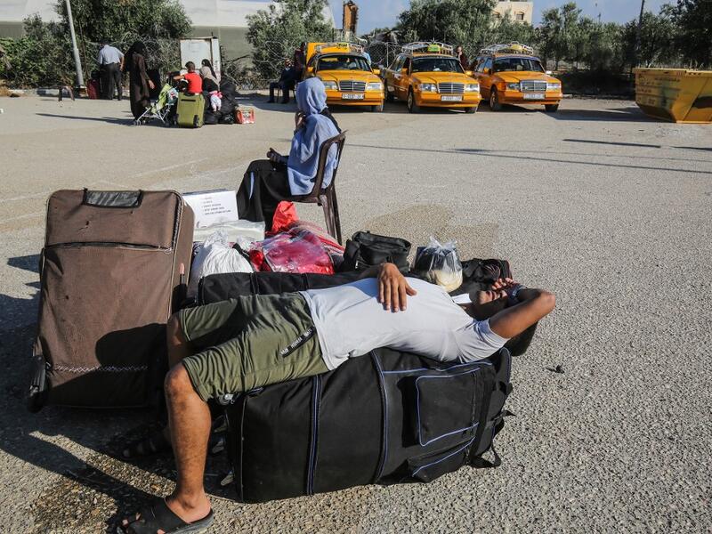 Palestinians rest as they wait to cross to the Egyptian side of Rafah border crossing after months of closure due to the coronavirus pandemic in the southern Gaza Strip, on August 11, 2020 . SAID KHATIB / AFP