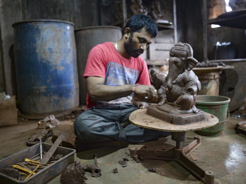 In this picture taken on August 11, 2020, an artisan prepares a clay idol of elephant headed Hindu god Ganesha at Muslim potter Yusuf Zakaria Galwani's workshop at Kumbharwada inside the Dharavi slums in Mumbai. After the coronavirus pandemic clobbered his pottery business, a Muslim artisan from India's largest slum turned to a Hindu god to revive his fortunes by making environmentally-friendly Ganesha idols for an upcoming festival. In Mumbai's Dharavi slum, Galwani worked alongside his two brothers to cre